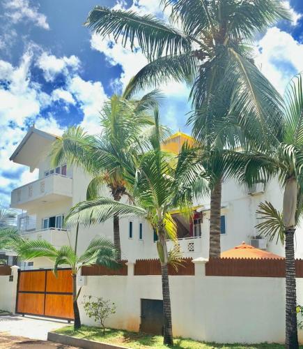 a white building with palm trees in front of it at Sonnige Ferienwohnung mit Wifi in Flic-en-Flac