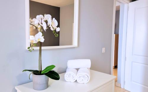a bathroom with white towels and a vase with flowers at Caléndula Beach 1ºLinea mar in Caleta de Sebo