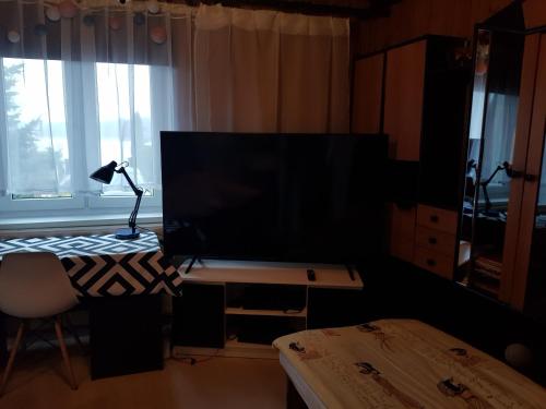 sala de estar con TV y escritorio con lámpara en Pokoje u Gosi, en Węgorzewo