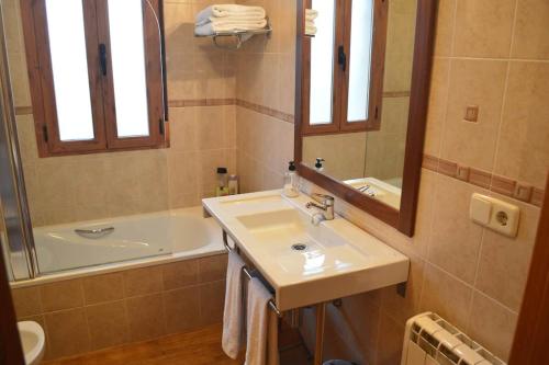 uma casa de banho com um lavatório, uma banheira e um espelho. em El Lagar em Fuentidueña