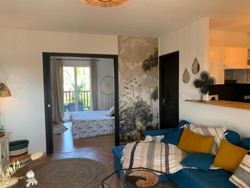 een woonkamer met een blauwe bank en een slaapkamer bij Villa carioca appartement bâbord in Gujan-Mestras