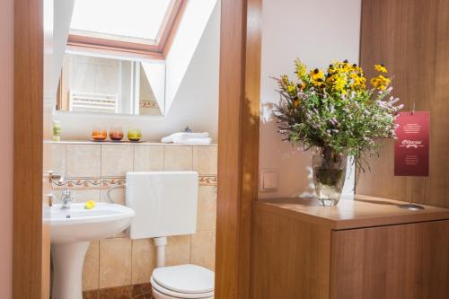 a bathroom with a toilet and a vase of flowers at Rooms & Restaurant Ostarija in Dolenjske Toplice