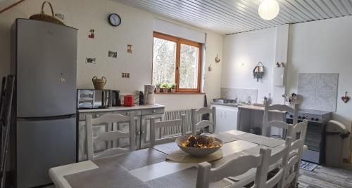 a kitchen with a table and chairs and a refrigerator at Gîte la source de la bruche in Bourg-Bruche