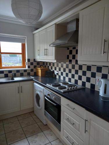 a kitchen with white cabinets and a stove top oven at Town Square Holiday Homes in Lisdoonvarna