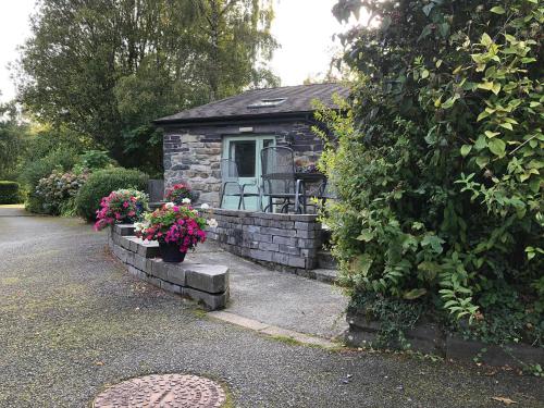a small stone house with flowers in front of it at Hafan Cottage at Bryn Llys in Bethesda