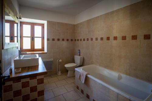 une salle de bain avec une baignoire, des toilettes et un lavabo dans l'établissement Le mas d'Orsan chambres d'hôtes, à Orsan