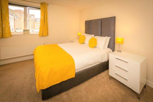 a bedroom with a large bed with a yellow blanket at Sailor's Rest - modern flat with water views in Pevensey