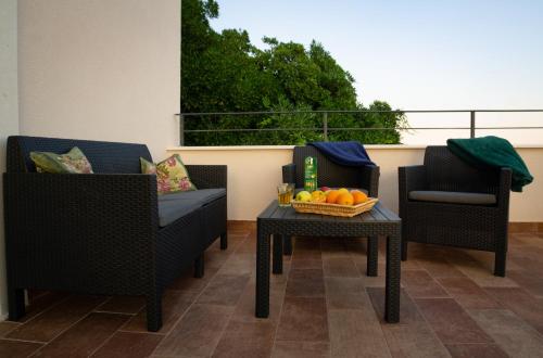 a patio with two chairs and a table with a bowl of fruit at Villa Ragusa in Dubrovnik