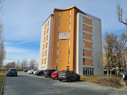 un gran edificio con coches estacionados en un estacionamiento en C&Y Apartments Aqua Park, en Mamaia