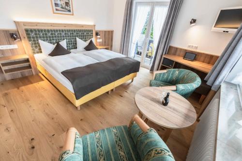 a hotel room with a bed and a table and chairs at Hotel Bellevue in Bad Wiessee