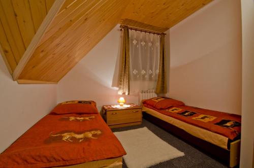 a bedroom with two beds and a table with a lamp at Prymulka in Zakopane
