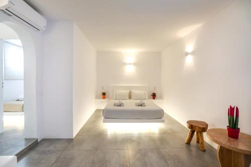 a white room with a bed and a table at Petinaros Hotel in Mýkonos City