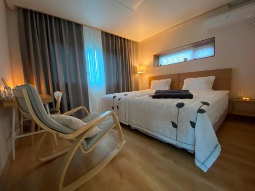 a bedroom with a large white bed and a chair at Jeju Time in Jeju