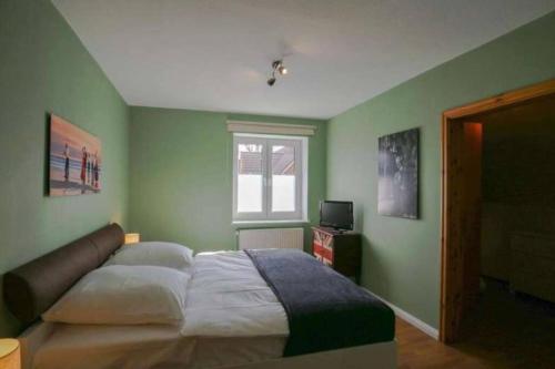 a green bedroom with a bed and a window at Schöne ruhige Ferienwohnung für die ganze Familie in Risum-Lindholm