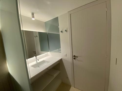 a white bathroom with a sink and a mirror at Ca l'Aiet in La Pobla de Lillet