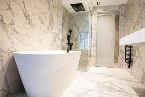 a bathroom with a white tub and marble walls at L’atelier 1927, au cœur de Reims in Reims