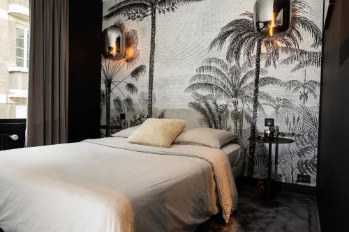 - une chambre avec un lit et un mur orné de palmiers dans l'établissement L’atelier 1927, au cœur de Reims, à Reims