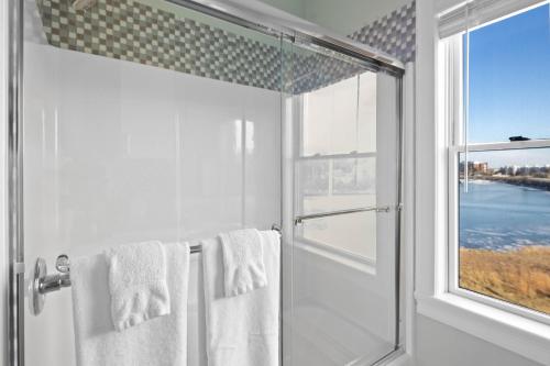 a bathroom with a shower with white towels and a window at The Beacon Waterfront Inn in Hull