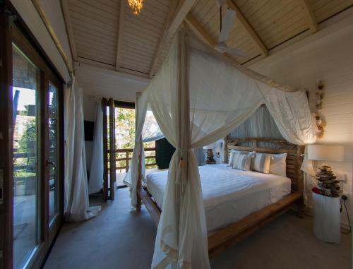 ein Schlafzimmer mit einem Himmelbett in einem Haus in der Unterkunft La Pointe Beach Huts in Praslin