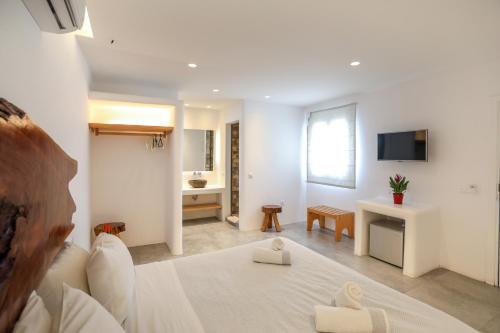 a white room with a bed and a bathroom at Petinaros Hotel in Mýkonos City