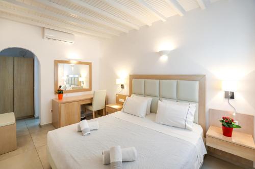 a bedroom with a large white bed and a desk at Petinaros Hotel in Mýkonos City