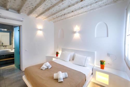 a white bedroom with two towels on a bed at Petinaros Hotel in Mýkonos City