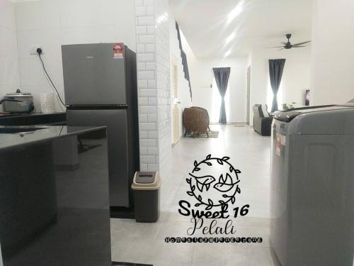 a kitchen with a refrigerator and a sign on the floor at Sweet 16 Pelali Homestay Pengerang (Wifi/Netflix) in Pengerang