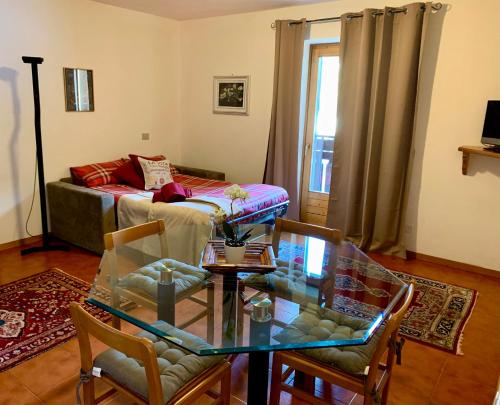 - un salon avec une table en verre et un canapé dans l'établissement Cima de’ Piazzi Apartment, à Isolaccia