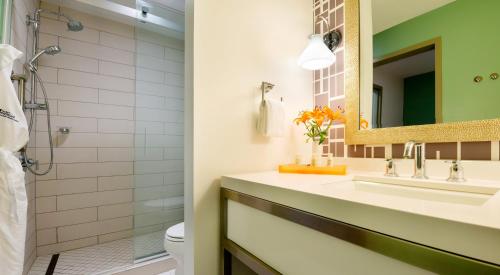 a bathroom with a sink and a mirror and a toilet at Hotel Indigo Savannah Historic District by IHG in Savannah