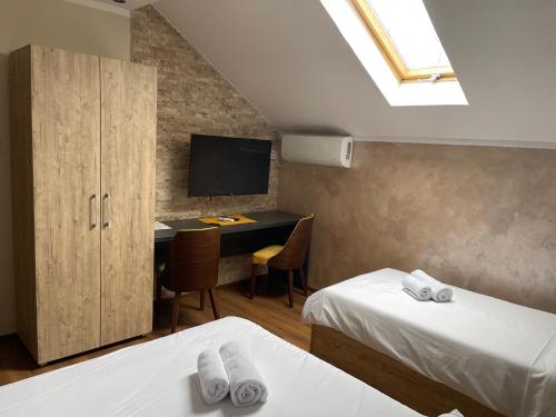 a bedroom with two beds and a desk with a television at Apartmani Mali vikend in Belgrade