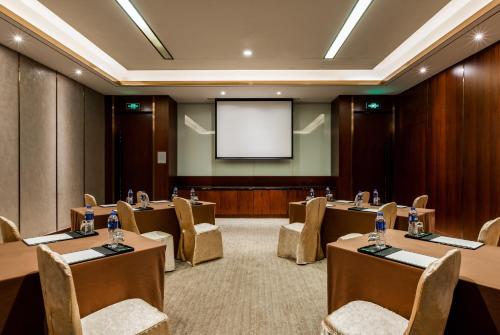 a conference room with tables and chairs and a screen at InterContinental Fuzhou in Fuzhou