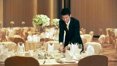 a man in a tuxedo is standing at a table in a dining room at InterContinental Fuzhou in Fuzhou