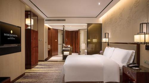 a bedroom with a large white bed and a television at InterContinental Fuzhou in Fuzhou