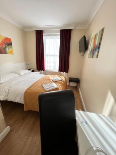 a hotel room with a bed and a chair at Melbourne House Hotel in London
