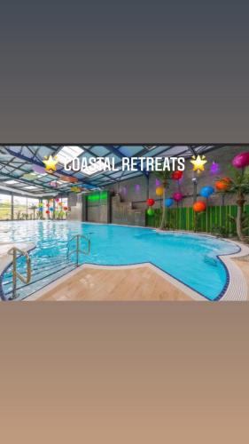 a large swimming pool in a building with a sign at Coastal retreats, Beech rise, primrose valley in Filey