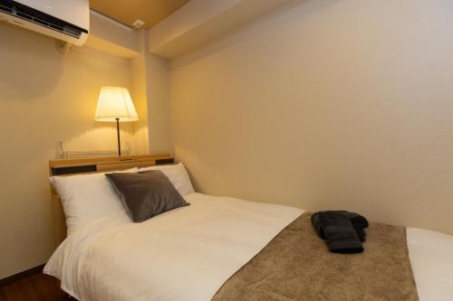 a bedroom with a white bed with a black bag on it at 唐沢ホテル Karasawa-Hotel in Tokyo