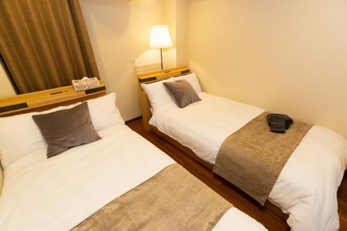 two beds in a small room with a lamp at 唐沢ホテル Karasawa-Hotel in Tokyo