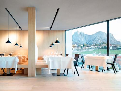 a dining room with white tables and a large window at Schgaguler Hotel in Castelrotto