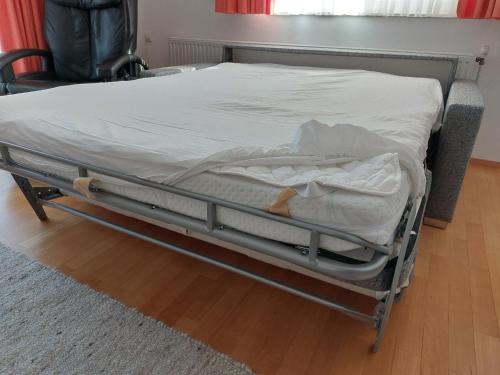 an unmade bed in a room with a chair at Ferienwohnung Metzler - Blick auf die Berge in Göfis