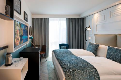 a hotel room with a bed and a desk at Hotel Indigo Dresden - Wettiner Platz by IHG in Dresden