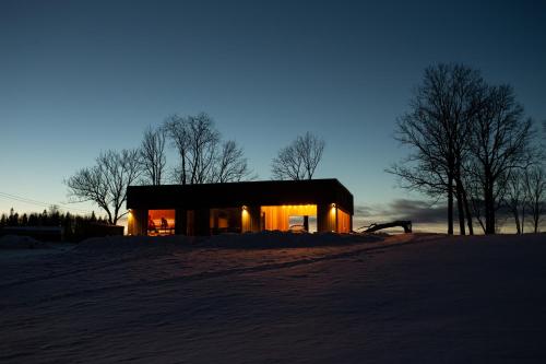 a house in the snow at night with the lights on at Ķestermuiža in Alūksne