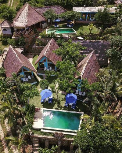 an aerial view of a resort with two pools and umbrellas at Blue Monkey Retreat Areguling Lombok in Kuta Lombok