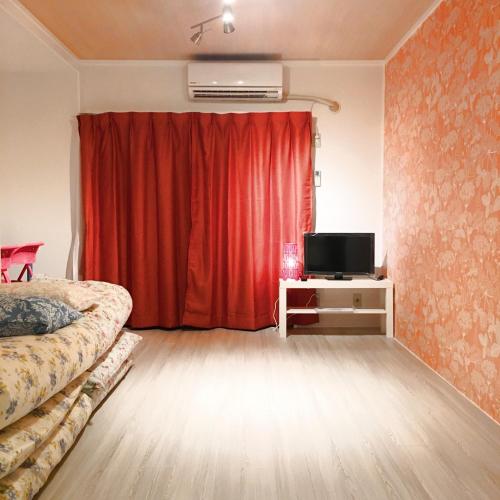 a bedroom with a red curtain and a television at Guest House Fukuoka W303 in Kasugabaru