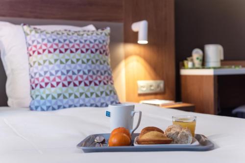 a tray of food and a cup of coffee on a bed at Campanile Epinal Centre - Gare in Épinal