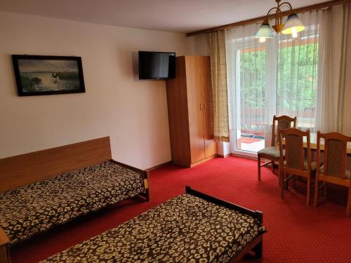 クルクランキにあるPanterej Pokoje Gościnneのベッド2台とダイニングルームが備わるホテルルームです。