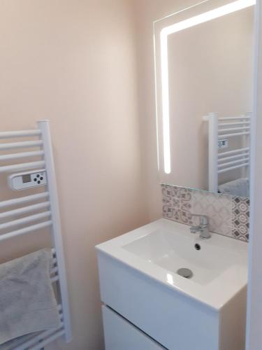 une salle de bain blanche avec un lavabo et un miroir dans l'établissement Maison charmante à Saint-Blimont avec jardin, à Saint-Blimont