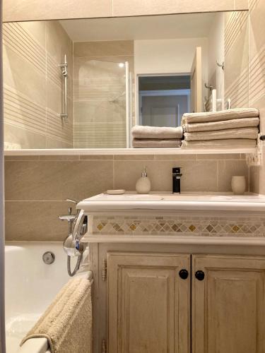 a bathroom with a sink and a mirror and a tub at Les Restanques coquelicot vue mer in Grimaud