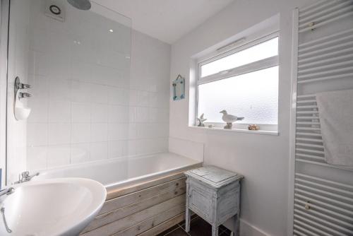 baño con bañera, lavabo y ventana en Sandy Lane Cottage in Reydon by Air Manage Suffolk, en Southwold