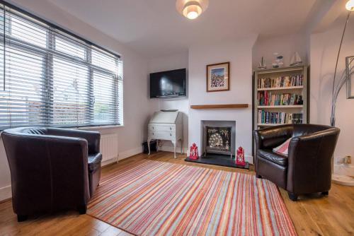 a living room with two chairs and a fireplace at Sandy Lane Cottage in Reydon in Southwold