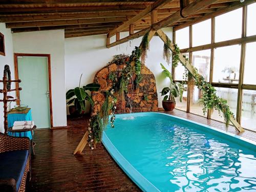 a swimming pool in a room with a stone wall at Chalés da Serra Catarinense in Bom Jardim da Serra